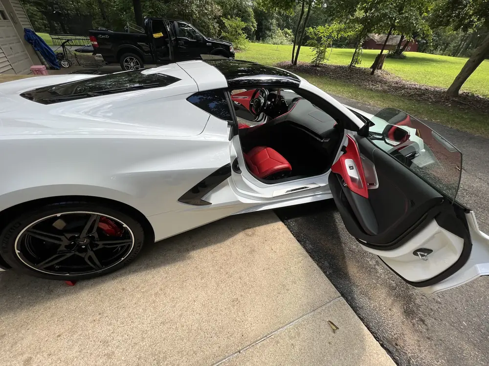 White Chevrolet Corvette with red interior, doors open, after a detail